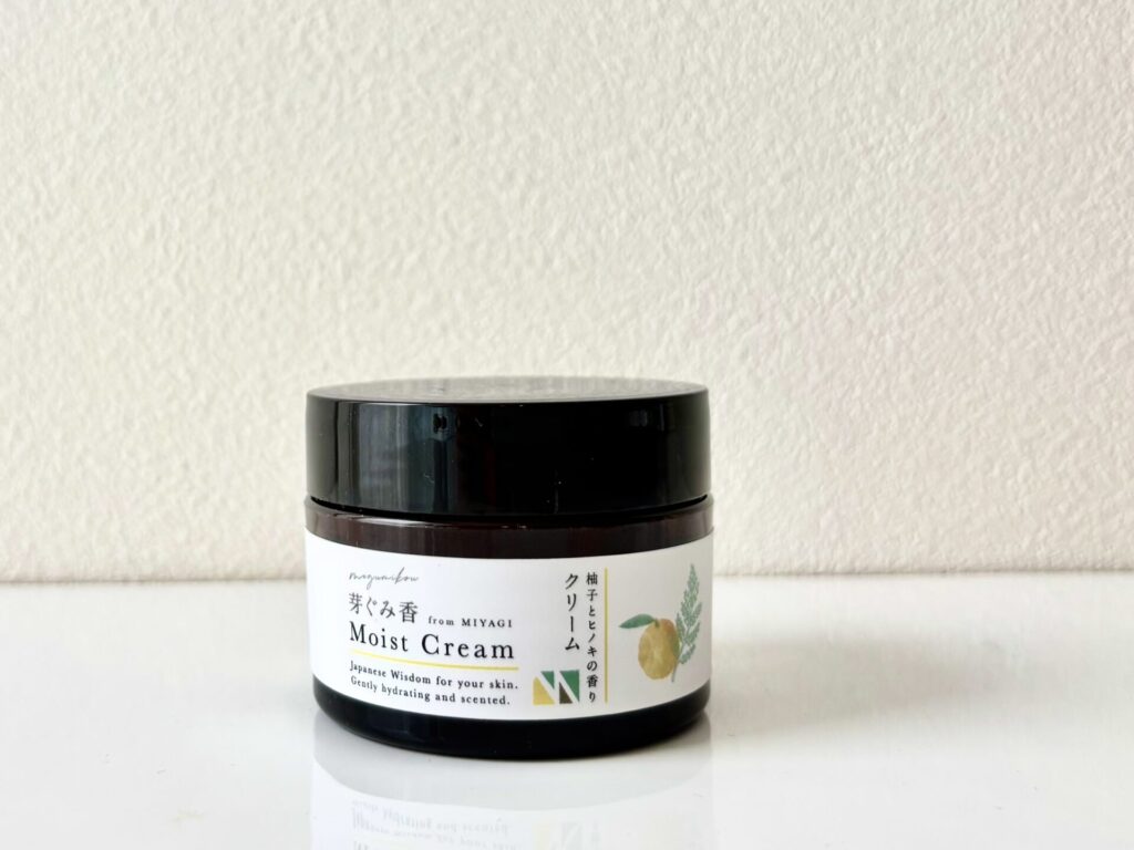 Dark glass jar with a black lid on a white surface, labeled 'Moist Cream' in English.